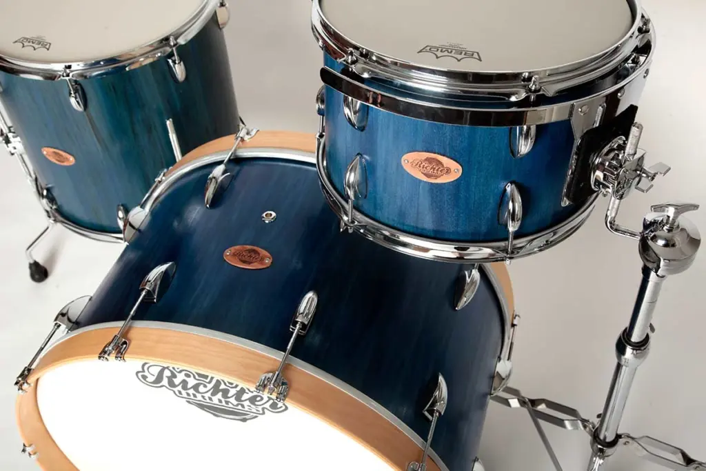 Schlagzeug-American whitewood Schlagzeug-Set aus Holz mit blauer Oberfläche, verziert mit 'Richter Drums-Logo und weißen Schlagfellen.