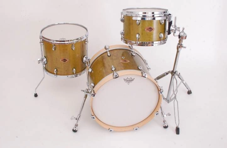Kirschholz-Schlagzeug-mit-Naturfinish-gruen. Schlagzeug-Set aus Kirschholz mit natürlichem Grün-Finish, bestehend aus Bassdrum, Floor Tom und Hängetom. Die Kessel sind mit Öllack veredelt und verfügen über Gussspannringe sowie ein Freischwingsystem für das Hängetom