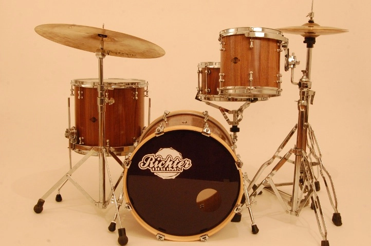 Schlagzeug-aus-Nussbaum Schlagzeug-Set mit Bassdrum, Snare, Hängetom und Floor Tom, alle mit edlem Holzfinish und verchromter Hardware.